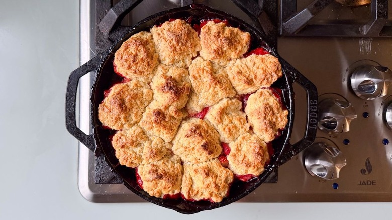 Strawberry and cardamom biscuit cobbler in cast iron skillet cooling on stovetop