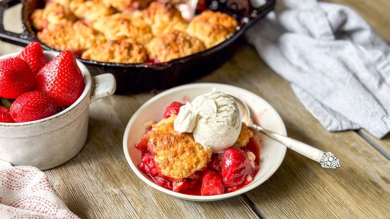 Strawberry and cardamom biscuit cobbler in serving bowl with vanilla ice cream