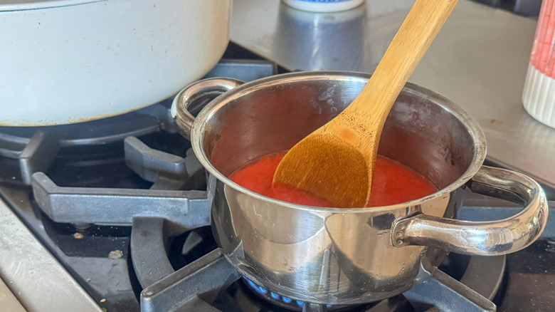wooden spoon stirring strawberry puree in pot