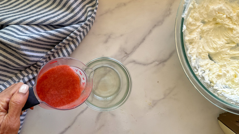 hand pouring strawberry puree into jar