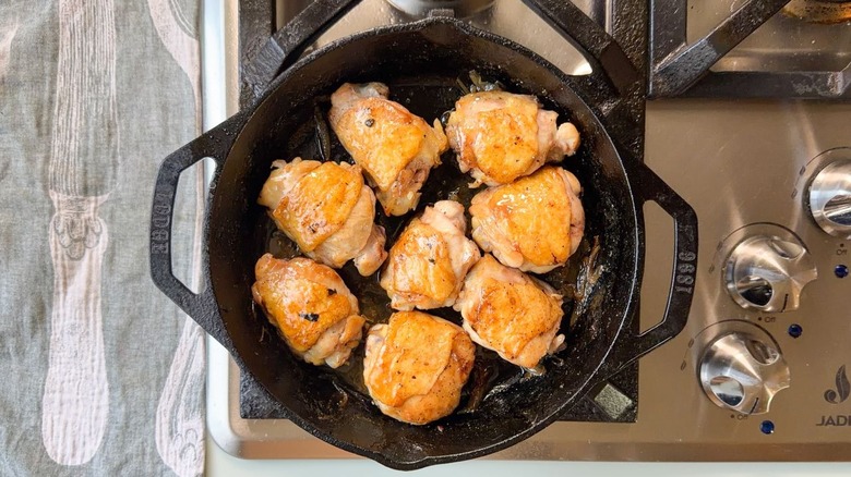 Glazed chicken thighs in cast iron skillet on stovetop
