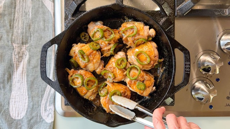 Glazed chicken thighs in cast iron skillet with charred jalapeños and shallots