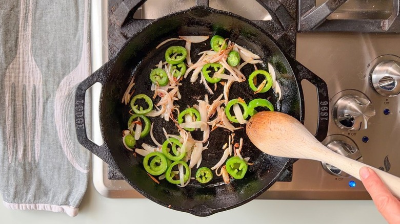 Charred sliced jalapeños and shallots in cast iron skillet