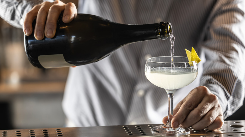 Bartender pouring Champagne into coupe glass