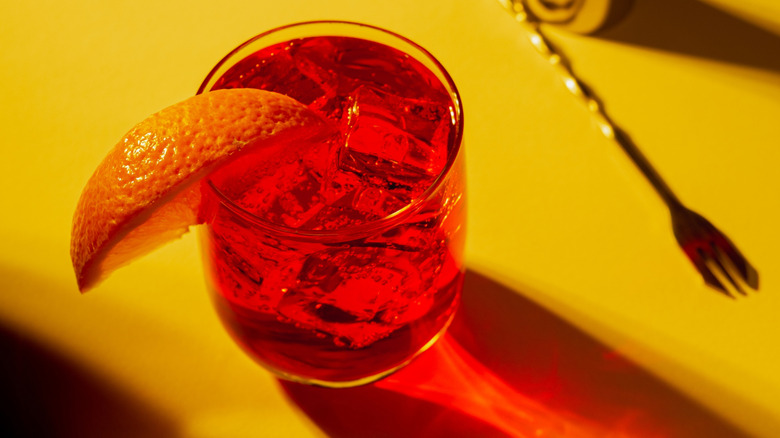 A negroni cocktail on a yellow surface