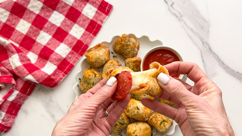 hands pulling apart pizza bite