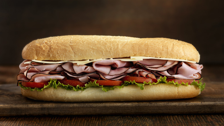 A subway sandwich with thinly sliced cuts and fresh vegetables