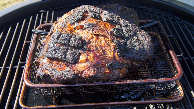 Smoked, encrusted pork shoulder on pan on charcoal grill