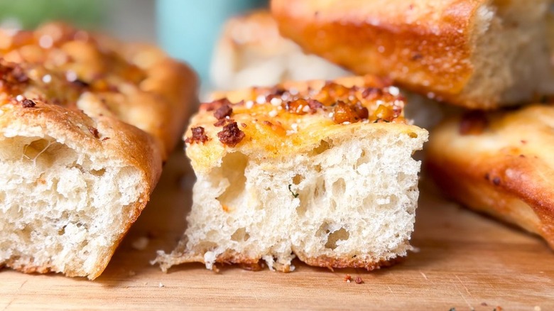 Close up of summer corn and roasted garlic focaccia squares on cutting board