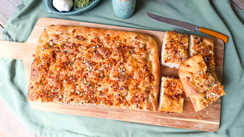 Summer corn and roasted garlic focaccia on cutting board with knife