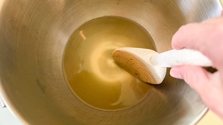 Stirring honey and warm water with a wooden spoon in a stand mixer bowl