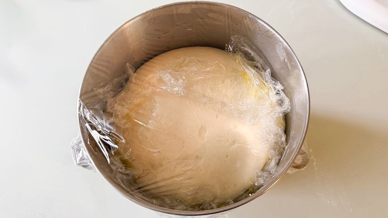 Focaccia dough rising in plastic-covered stand mixer bowl