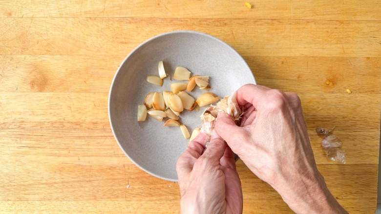 Squeezing roasted garlic cloves from head into a small bowl
