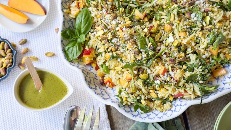 Summery grilled corn and orzo salad in serving dish with dressing on the side