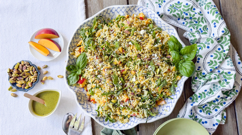 Summery grilled corn and orzo salad recipe in serving dish with dressing and garnishes