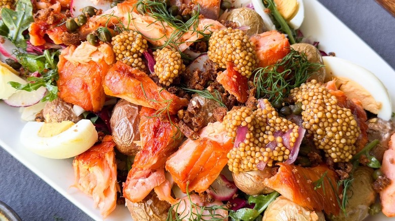 Close up of pickled mustard seeds and red onions on summery hot-smoked salmon salad