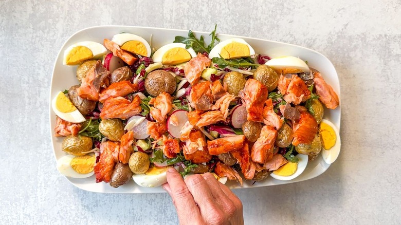 Summery hot-smoked salmon salad with hard boiled eggs and potatoes on serving platter