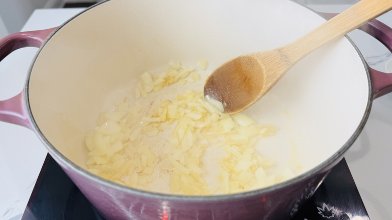 chopped onions in a pot with a wooden spoon