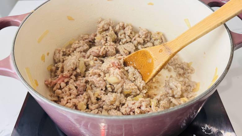 crumbled cooked sausage in a pot with a wooden spoon