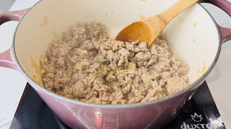 crumbled cooked sausage in a pot with a wooden spoon