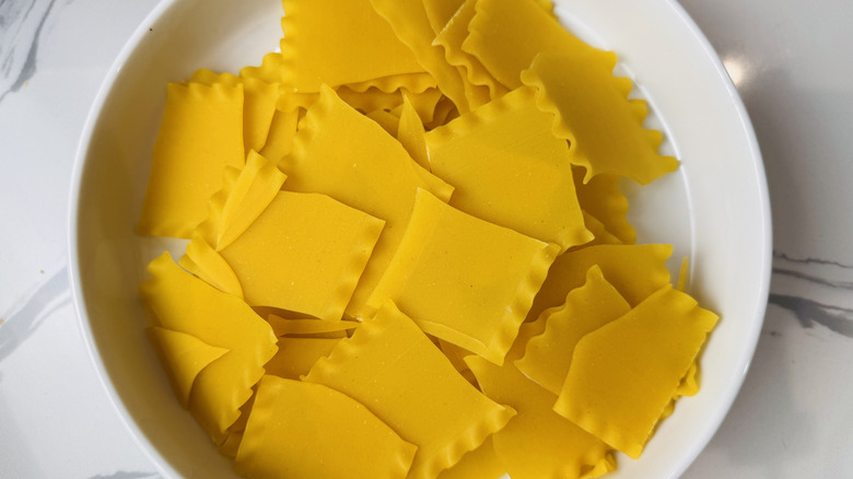 uncooked broken lasagna noodles in a white bowl