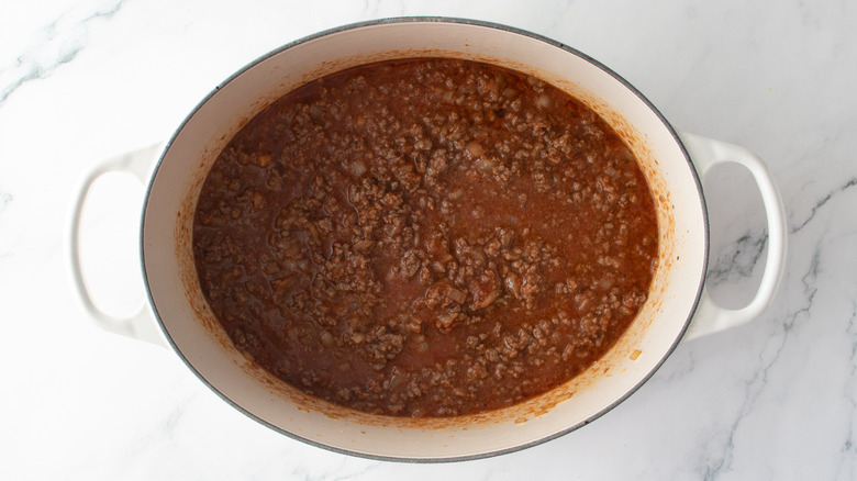 Tomato sauce, broth, and ground beef in a Dutch oven