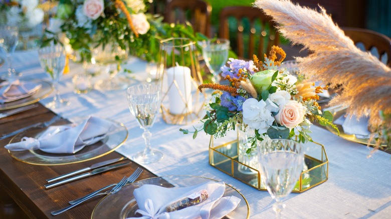 Elegant table set with dinnerware and centerpieces with purple, white, and pink flowers