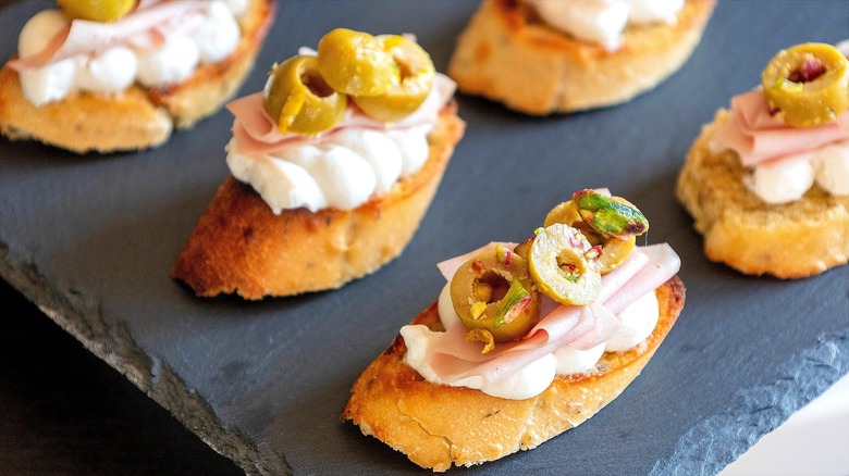 Crostini with ricotta, mortadella, and sliced green olives