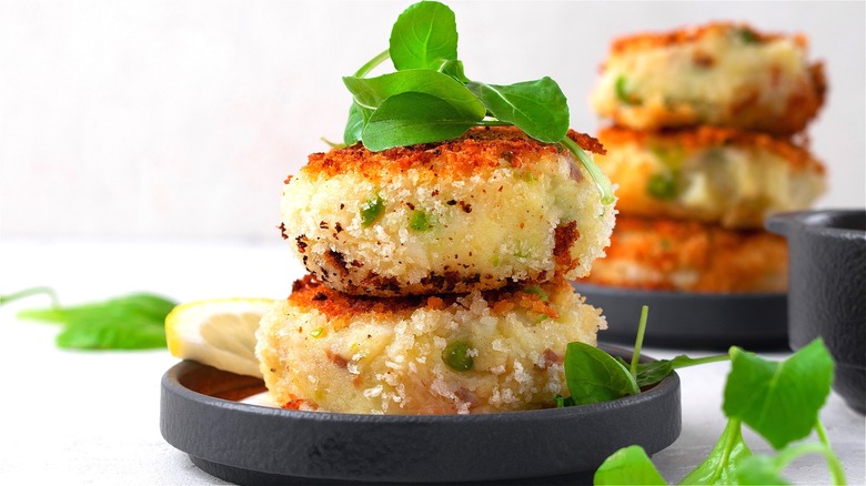Two fish patties covered in toasted breadcrumbs and fresh greens