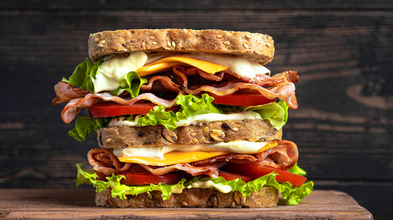 A multi-layer sandwich filled with meats, cheeses, lettuce, tomatoes, and spread