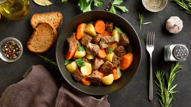 A black bowl filled with pot roast surrounded by sides and seasonings.