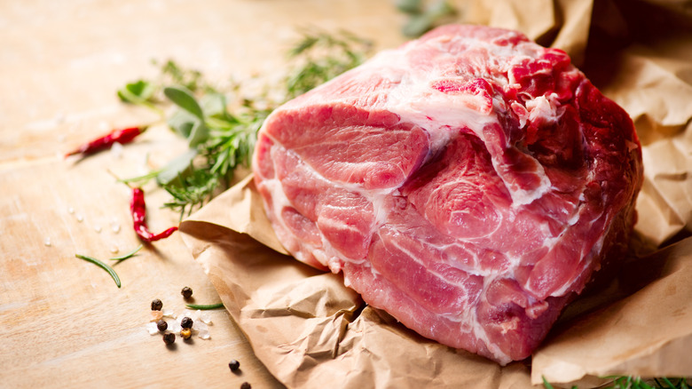 A raw cut of pork shoulder on brown paper.