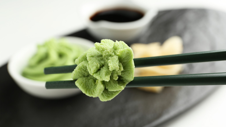 A pair of chopsticks holding a small serving of wasabi