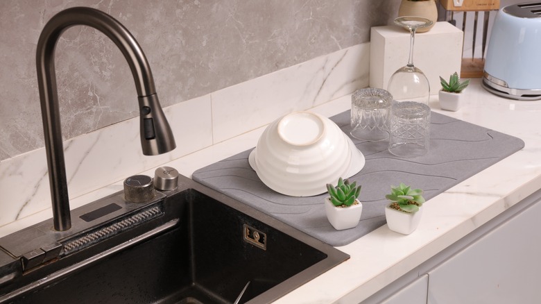 grey dish drying mat on a white marble counter