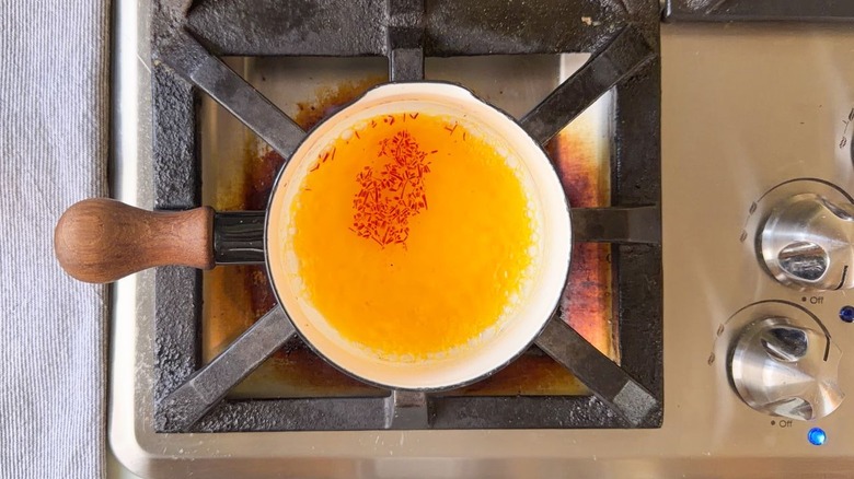 Small pot of boiling water with saffron threads on stovetop