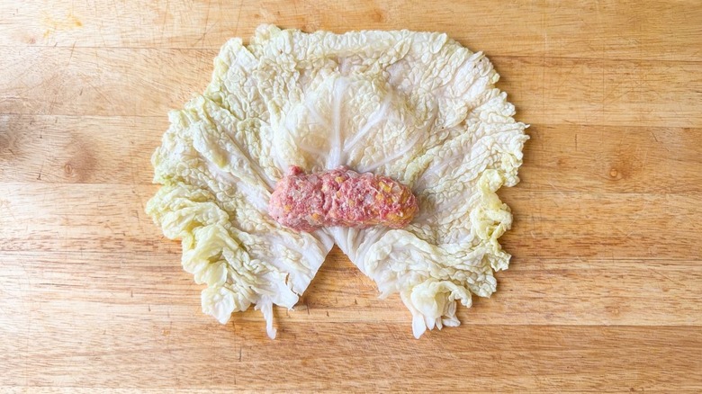 Cylinder-shaped meat filling on large blanched savoy cabbage leaf