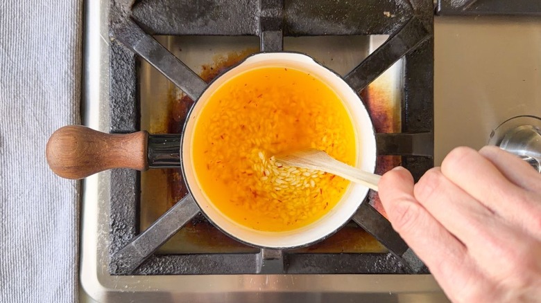 Stirring rice in saffron broth in pot on stovetop
