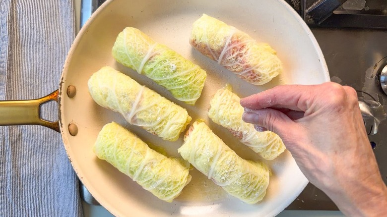 Sprinkling sugar on 6 cabbage rolls in skillet on stovetop