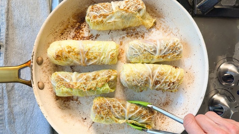 Browning Swedish-inspired stuffed cabbage rolls in skillet with tongs