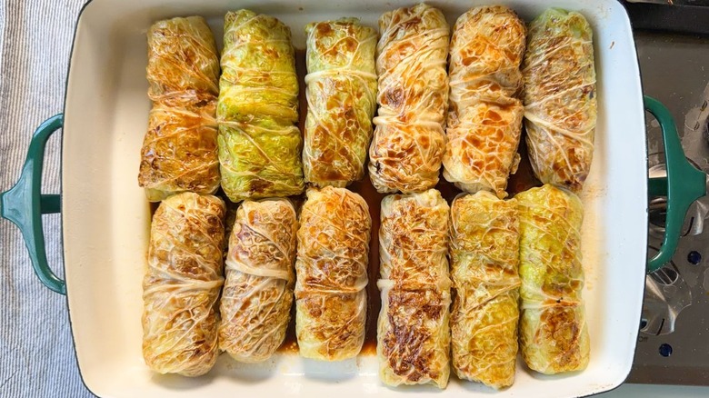 Browned Swedish-inspired stuffed cabbage rolls in baking dish with beef broth