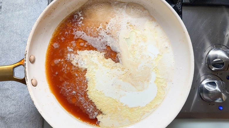 Beef stock, melted butter, and cream boiling in skillet