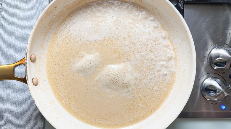 Beef broth, heavy cream, and butter sauce in skillet on stovetop