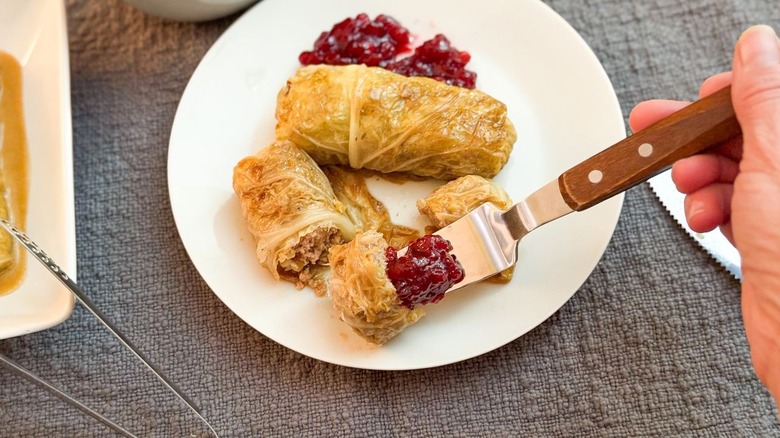 Swedish-inspired stuffed cabbage rolls on plate with lingonberries and bite on fork