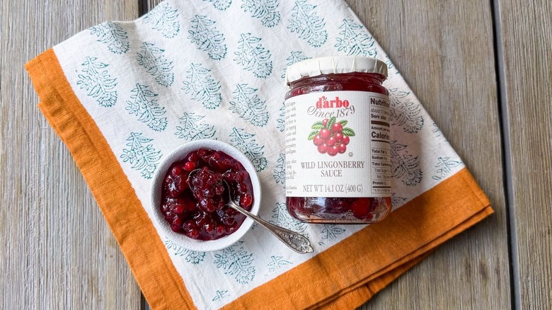 Wild lingonberry sauce in jar and bowl with spoon and napkin