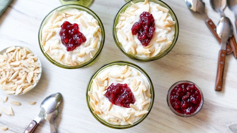 Swedish-style rice pudding with sliced almonds and lingonberries in serving glasses with spoons