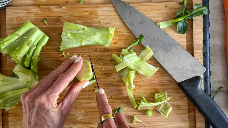 hands trimming broccoli stems with knife