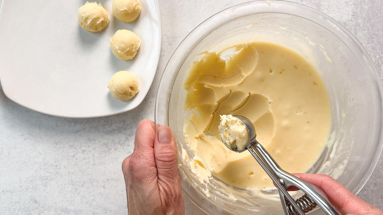 Scooping white chocolate meyer lemon ganache with cookie scoop onto plate