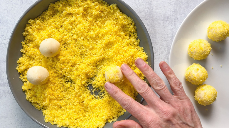 Rolling white chocolate meyer lemon truffles in lemon sugar in bowl
