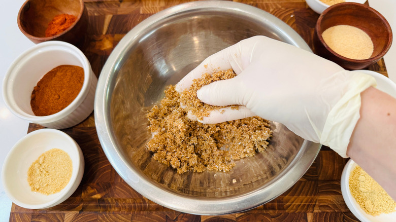 Gloved hand holding brown sugar over bowl