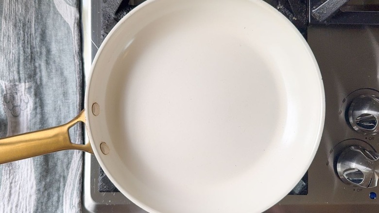 White non-stick saute pan with gold handle on stovetop